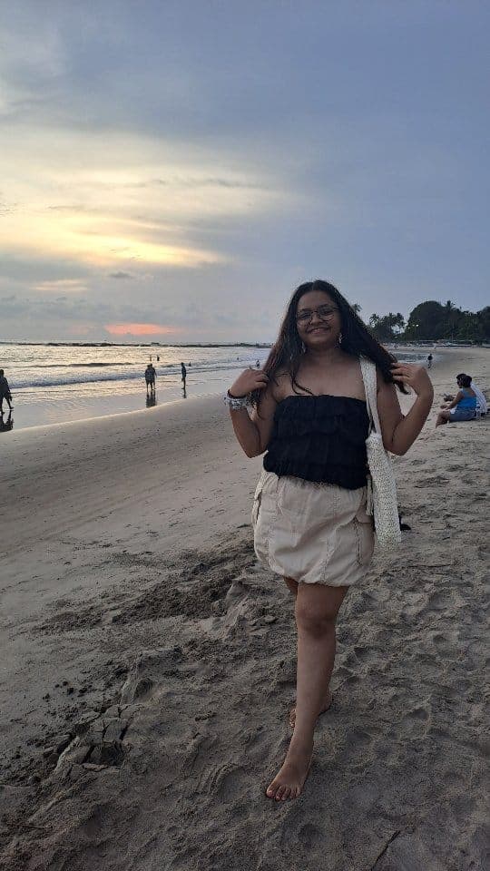 Irika Goyal walking barefoot on a beach at sunset